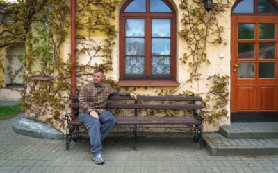 A man sitting on a bench beside an ivy-covered building in Pinsk, Belarus. Captured in an urban outdoor setting.