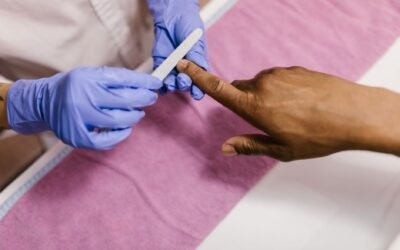Close-up of a manicurist using a nail file on a client's hand during a salon session.