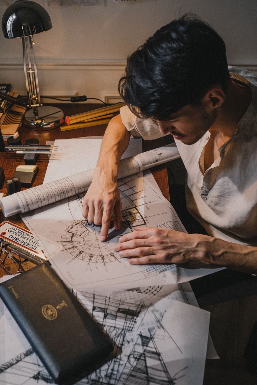Architect sketching architectural plans with tools in a creative workspace setting.