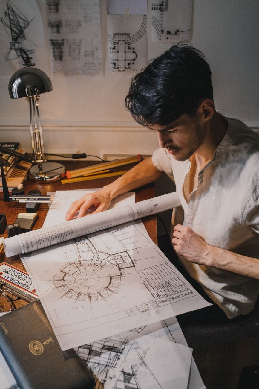 Caucasian man reviewing architectural blueprints in a well-lit office environment.
