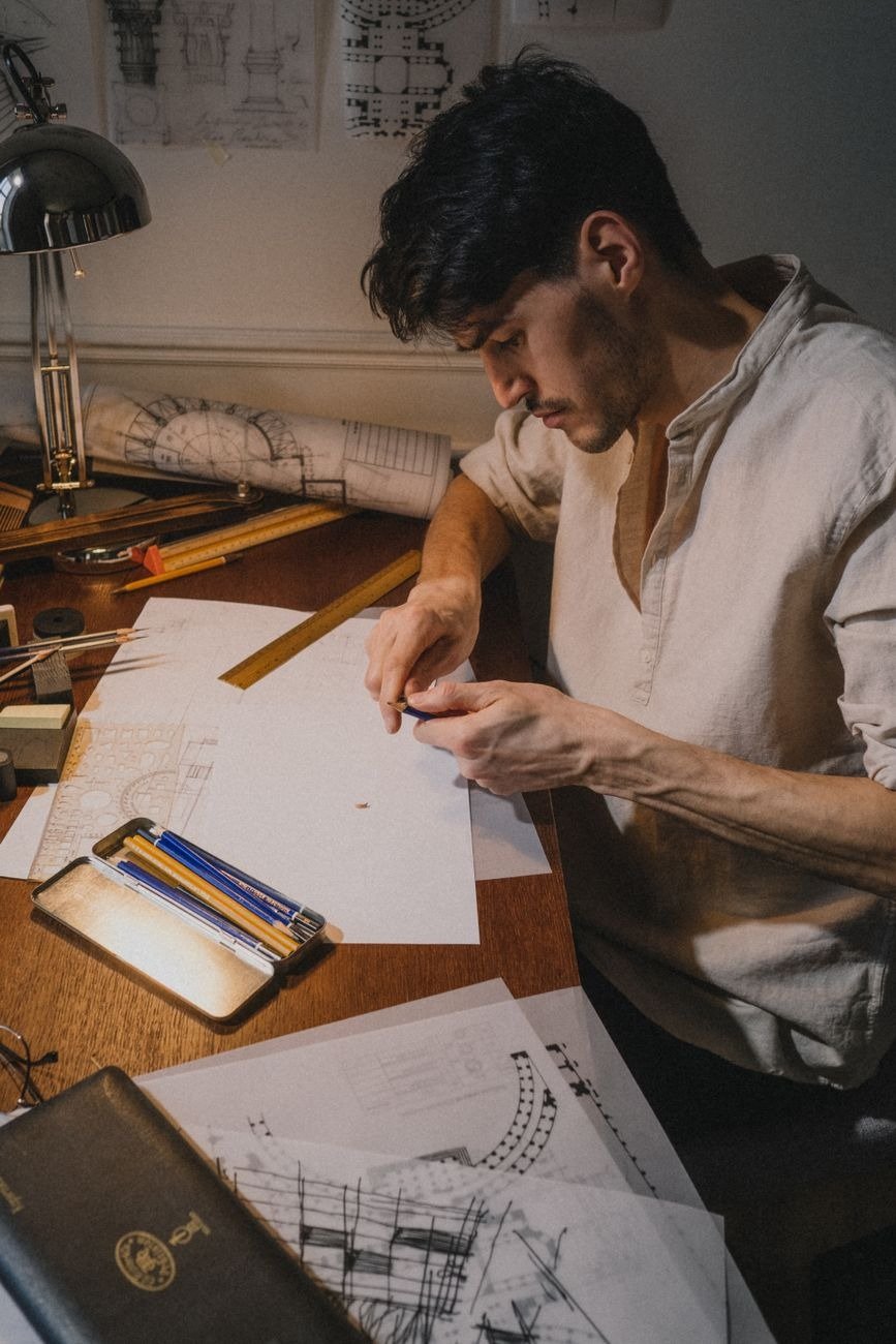 Man focused on architectural drawing at a desk, indoors.