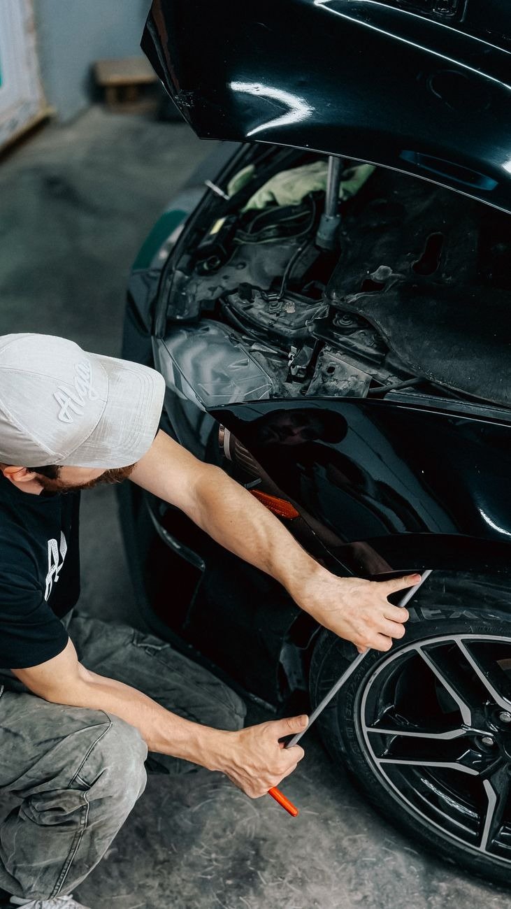 Mechanic working meticulously on a car bumper repair inside an auto garage.