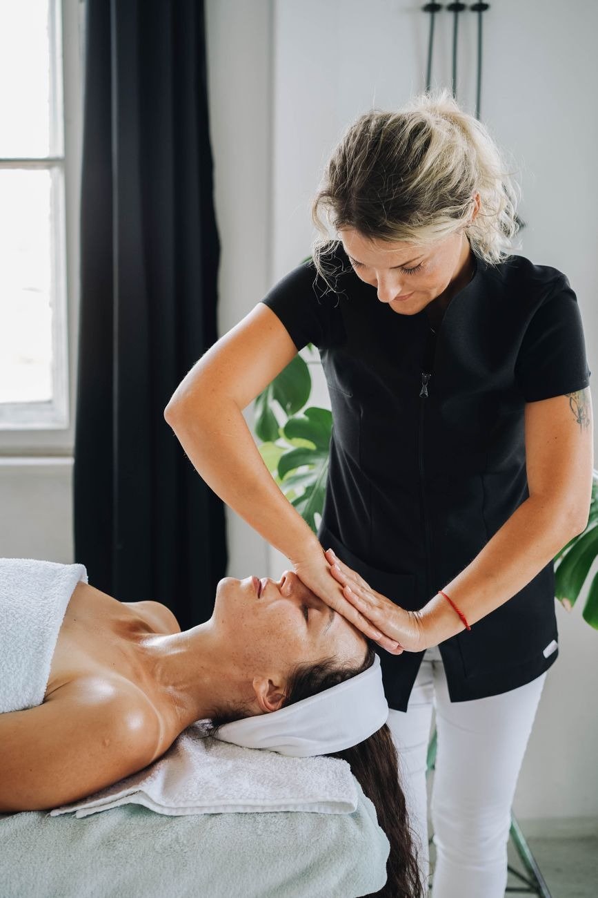 Woman receiving a calming face massage at a spa, promoting relaxation and wellness.