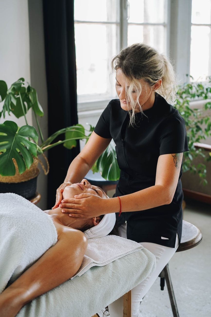 A soothing face massage session in a serene spa with natural light and plants.
