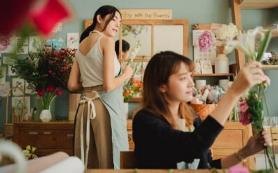 Focused multiethnic women in aprons working in cozy floral shop with various fresh flowers