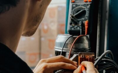 Electrician using a multimeter to check voltages in an industrial setting.