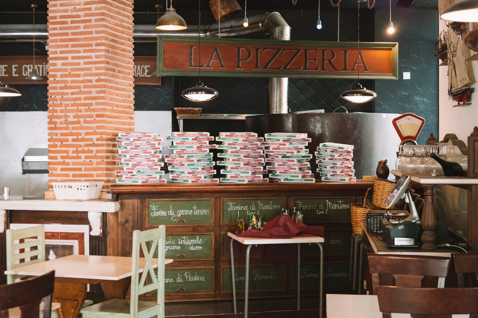 Cozy pizzeria interior with stacked pizza boxes and rustic decor in Valencia, Spain.
