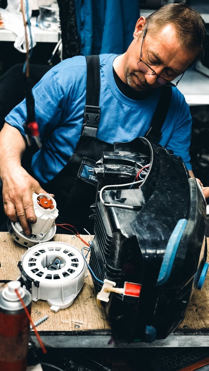 Experienced technician focused on repairing an electrical machine in a workshop setting.