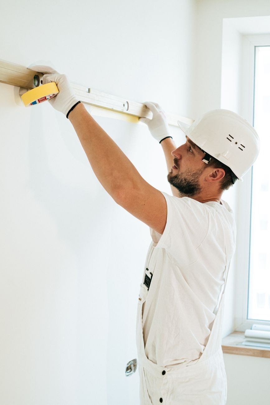 A construction worker using a spirit level to ensure accuracy on a wall installation.